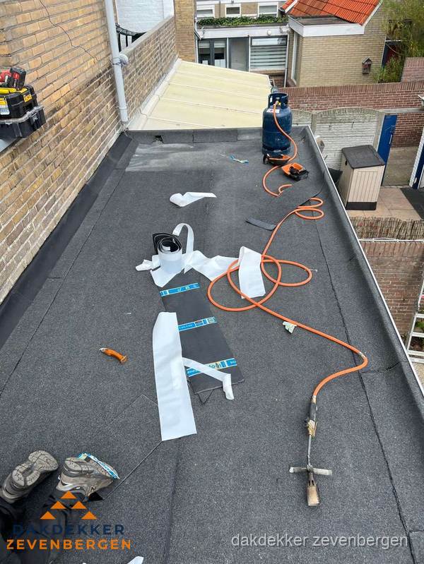 Dakdekkers bezig met bitumen dakbedekking in Zevenbergen
