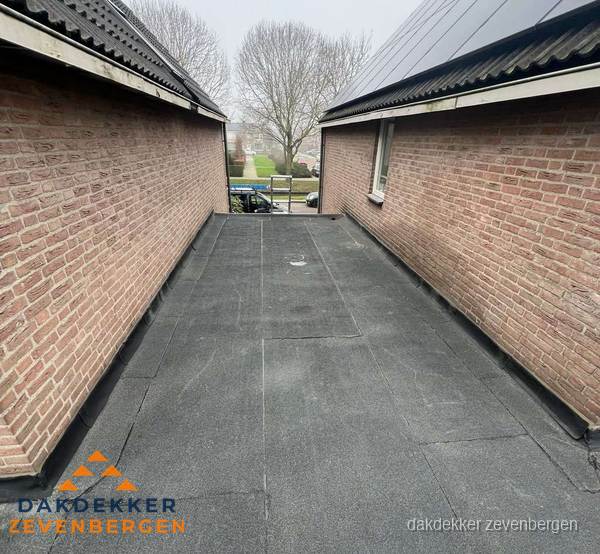 Plat dak met bitumen dakbedekking tussen bakstenen muren in Zevenbergen Plat dak met bitumen dakbedekking tussen bakstenen muren in Zevenbergen