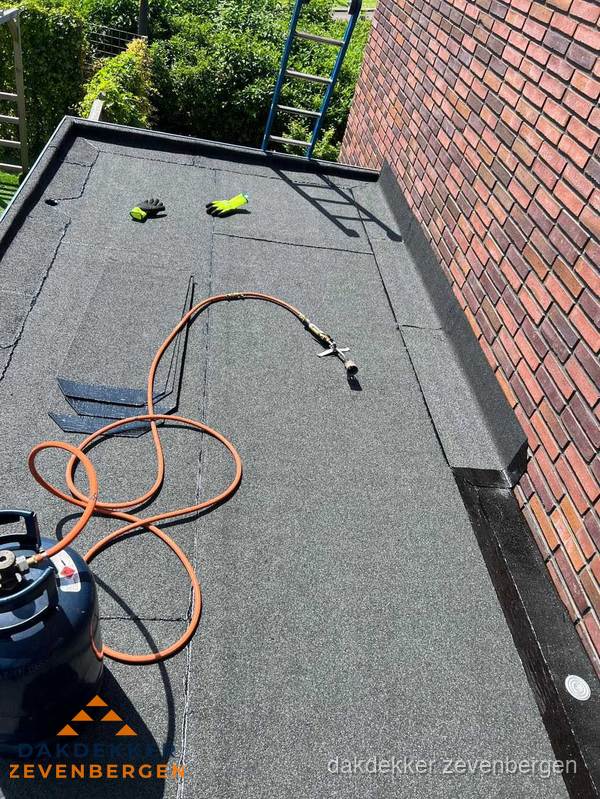 Plat dak met bitumen en brandgereedschap van dakdekkersbedrijf in Zevenbergen