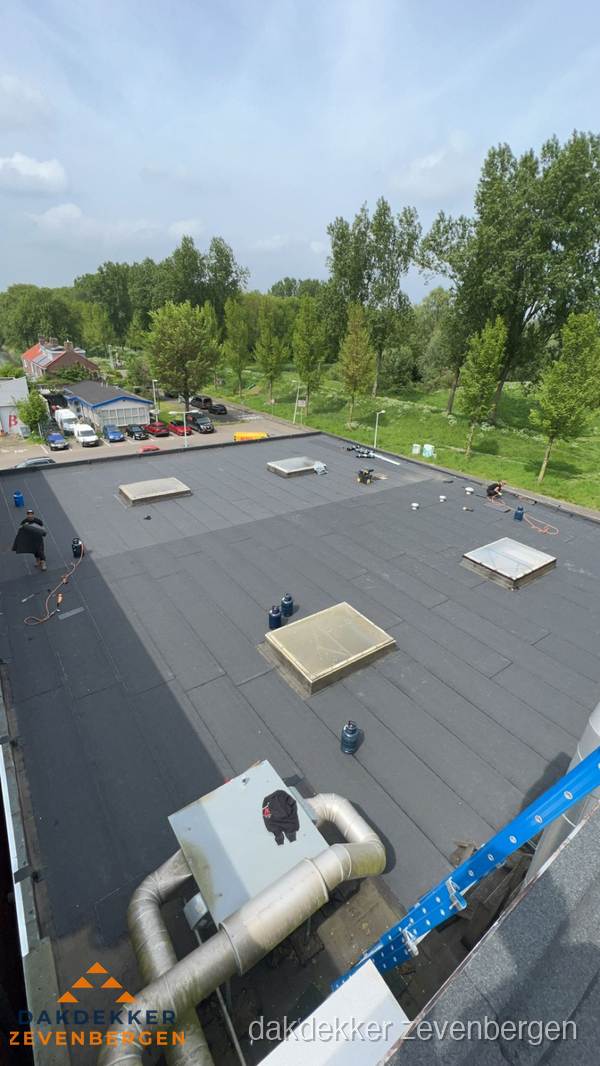 Dakdekker aan het werk op groot plat dak met bitumen in Zevenbergen Dakdekker aan het werk op groot plat dak met bitumen in Zevenbergen